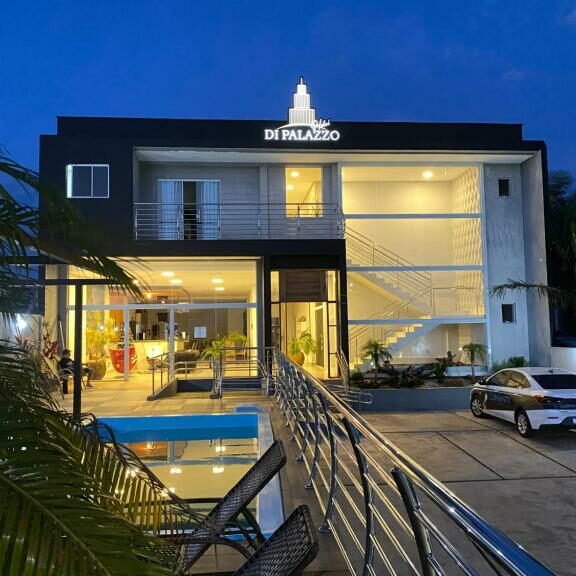 hotéis em Ametista do Sul RS Prédio de hotel moderno onde ficar em Ametista do Sul ao anoitecer com sinalização iluminada, varanda, piscina e carro estacionado na frente.