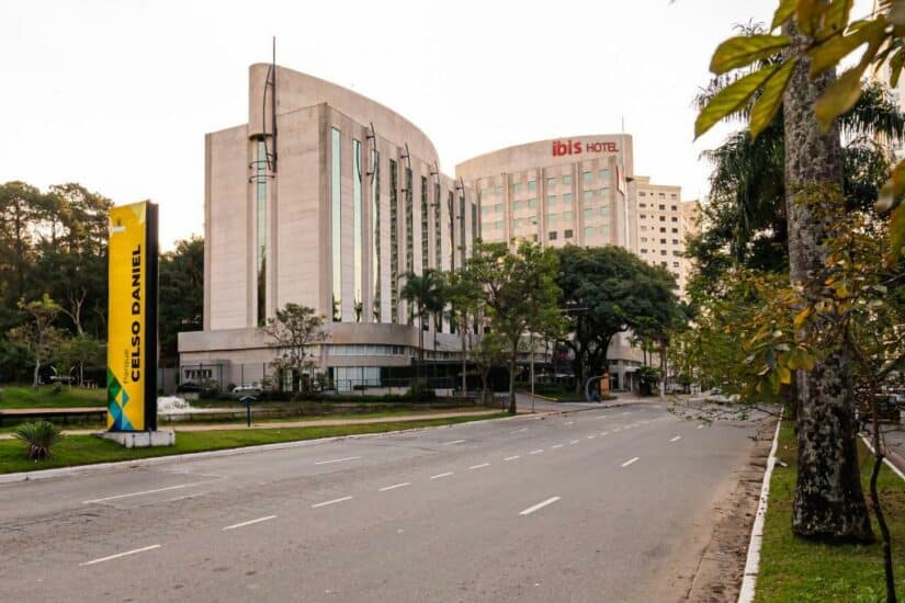 onde ficar em Paranapiacaba em São Paulo Edifício curvo do hotel Ibis com árvores e uma grande placa de sinalização da Avenida Celso Daniel.