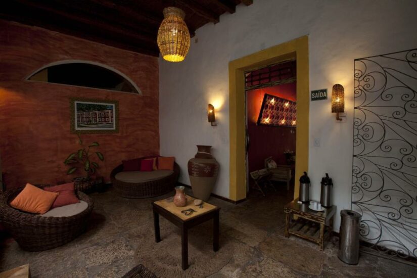 Sala aconchegante com móveis de vime onde ficar em São Luís do Maranhão, iluminação aconchegante, decoração rústica e uma pequena estação de café ao lado da porta.