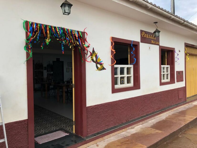 onde ficar em Diamantina Minas Gerais Um edifício branco com acabamento vermelho decorado com serpentinas coloridas e uma máscara para uma comemoração festiva.