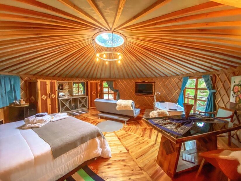 São Joaquim hospedagem Interior de yurt aconchegante com cama, sofá, banheira, piso de madeira e claraboia - onde ficar na Serra Catarinense.