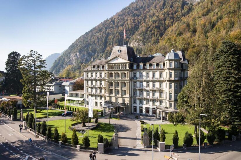 hotéis em interlaken ost na Suíça Grande hotel histórico Onde ficar em Interlaken com gramados bem cuidados, tendo como pano de fundo uma montanha arborizada em um dia ensolarado.
