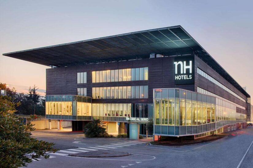 melhores hotéis na Itália em Orio al Serio O moderno edifício com fachada de vidro da NH Hotels ao entardecer, ideal para quem procura onde se hospedar em Bérgamo.