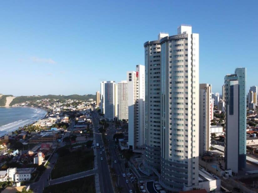 Edifícios altos e modernos se alinham ao longo de uma rua da cidade litorânea — perfeito para quem procura onde ficar em Ponta Negra, perto da praia.