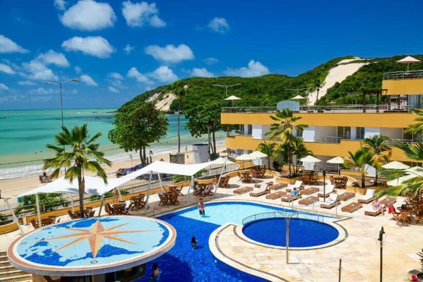 Hotel à beira-mar com piscina, espreguiçadeiras e palmeiras — onde ficar em Ponta Negra para relaxar sob o céu azul.